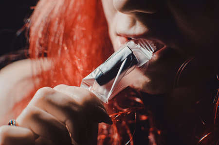 Red-haired sexy girl in a cafe smoking a hookah dressed in black bodyの写真素材