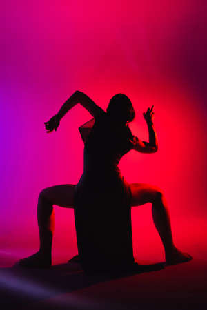 Modern teen contemporary dancer poses in front of the studio background in crimson violet tones with...