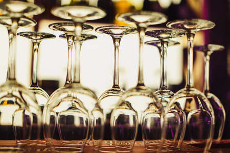 Many empty wine glasses on the counter in the light of the bar in the frontの写真素材