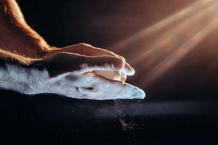 Male powerlifter hand in talc. palm preparation before lifting weights. Toned image. Hands in chalk. another view with the lightの写真素材