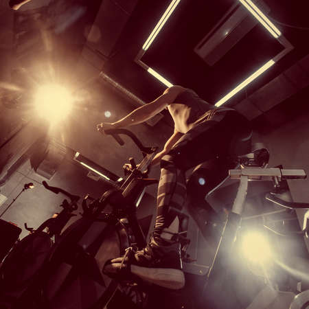 A bicycle simulator in the gym. Toned image. The is exercising on a stationary bike. bottom from the back viewの写真素材