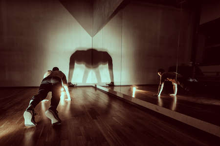 Attractive muscular man doing push-ups on a wooden floor. Toned image. The man is exercising in the gymの写真素材