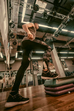 Man doing step up jumps in health club. Toned image. The man is exercising on the stepperのeditorial素材
