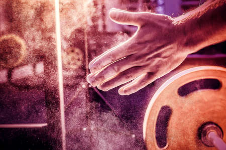 Male powerlifter hand in talc. preparation before lifting weights. Toned image. Hands in chalk. With...
