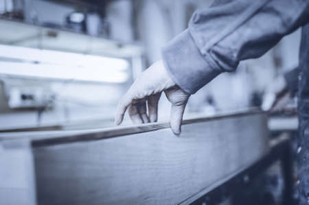 Man collects furniture details in the carpentry shop. Toned image. Gluing furniture parts using glue. close up viewの写真素材