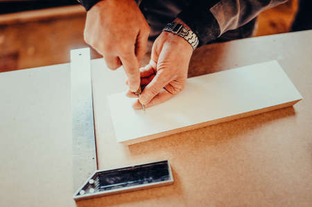 The carpente makes hole with an awl on a furniture details Toned image. makes a mark for the hole with an awl. from the top view with the try squareの写真素材