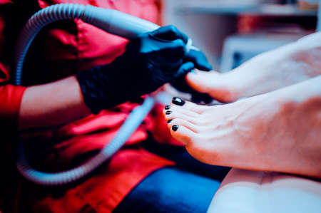 The process of pedicure in a professional beauty salon. Toned image. hardware processing of toes. from the side viewの写真素材