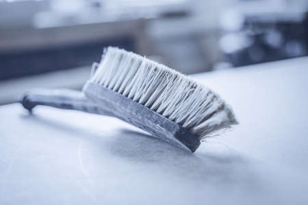Working brush cleaning note is on the table in the workshop. Toned image. Cleaning Brush desk wood...