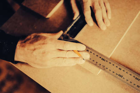A carpenter uses a framing square for marking a hole in a furniture part. Toned image. puts the point on the detail. another viewの写真素材