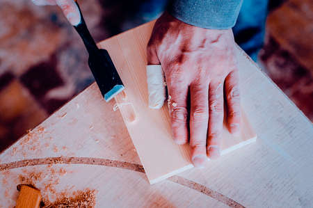 The carpenter uses a chisel to handle the edges of the product. Toned image. from the top viewの写真素材