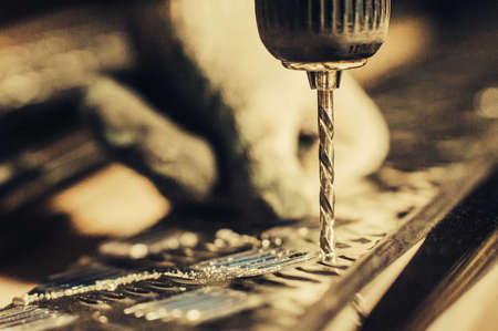 Drill screwdriver workflow creation of metal parts. male metal worker using drillpress. Toned image. macro viewの写真素材