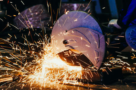 Worker cutting metal. Cutting metal angle grinder. Toned image. shearing metal parts metal sparks close. with the sparks viewの写真素材