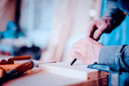 The carpenter uses a chisel for carving. Carving view. Toned image. close up view