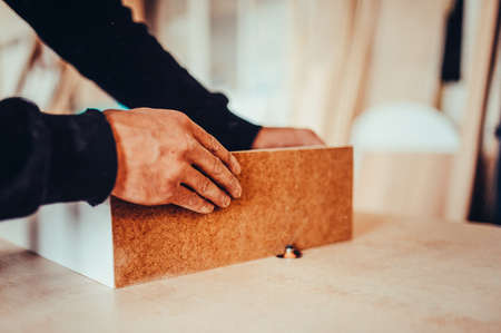 Worker uses a grinding machine. Toned image. Process of processing the edges of a furniture product on a special grinding machine.の写真素材