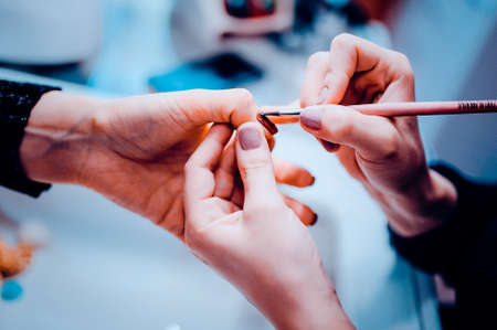 Manicure in beauty salon. Selective focus on brush. Toned image. Manicure processの写真素材