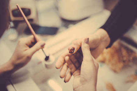 Manicure in beauty salon. Selective focus on brush. Toned image. Manicure process close up viewの写真素材