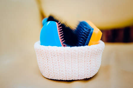 Basket with combs and round hair brushes. Toned image. Comb for combing raw hair in a basket in a hair salon. close up viewの写真素材