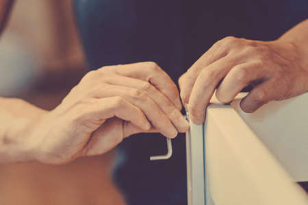 Joiner collects a new baby cot with a hand tool. carpenter collects a cot. Toned image. collects the walls of the crib using a hand hexagon. fixes the pendulum of a cot. from the front view closeの写真素材