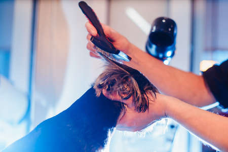 Female groomer haircut yorkshire terrier on the table for grooming in the beauty salon for dogs. tprocess of combing a dog's hair with a special comb from the side view closeupの写真素材