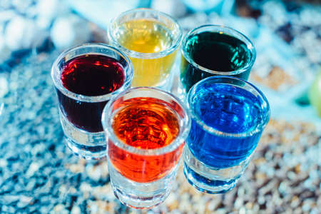 Party and holiday celebration concept. Image of multicolored liqueurs in shots on a wooden stand behind the bar. from the top view close upの写真素材