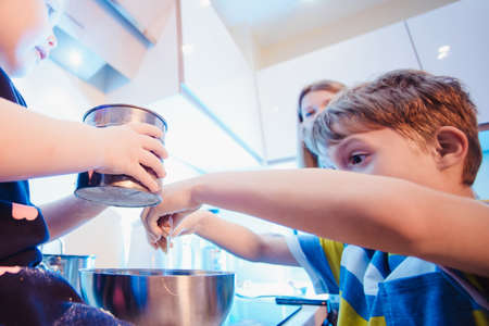family, children, hapiness and people concept. family with children having fun in the kitchen preparing pancakes from the side closeの写真素材