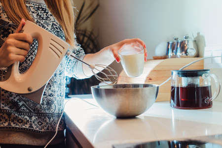 family, children, hapiness and people concept. Happy family with children preparing pancakes in the kitchen. Mom prepares dough for pancakes by mixing ingredients in a bowl with a mixerの写真素材