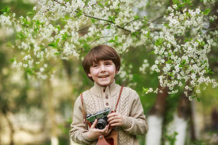 Portrait of a smiling cute boy taking picture with retro camera, spring timeの写真素材