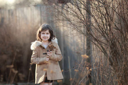 baby girl in a coat walks in the park in springの写真素材