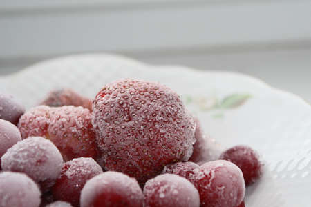 Frozen cherries and strawberries on a white plateの写真素材