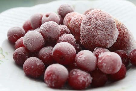 Frozen cherries and strawberries on a white plateの写真素材