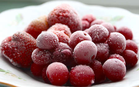 Frozen cherries and strawberries on a white plateの写真素材
