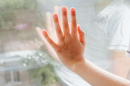 young baby boy looking through a window, child's hand on the windowの写真素材