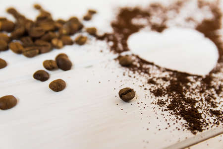 Heart made of instant coffee. Ground coffee and whole coffee beans on a whiteの写真素材
