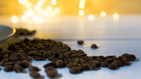 Whole grains of coffee on a wooden table against the background of defocused lights of the Christmas garland. Creative coffee conceptの写真素材