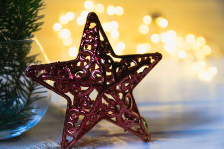 Christmas toy red star but against the background of defocused lights of a garlandの写真素材