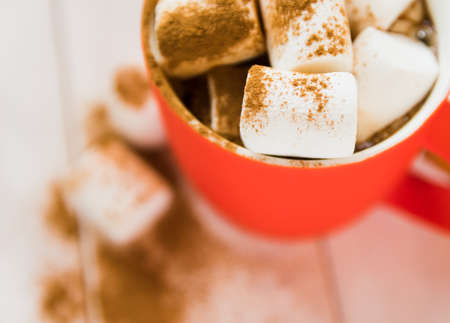 Top view of coffee with marshmallows and cinnamon in a red cup. The concept of cozy New Year and...
