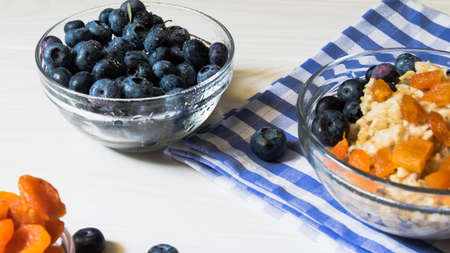 Ingredients for a wholesome healthy breakfast. Fresh blueberries, dried apricots and oatmeal