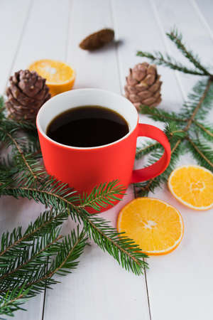 Red cup with a hot drink next to spruce branches and dried lemon slicesの写真素材