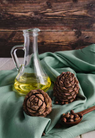 Cedar oil in a transparent glass bottle, pine cones and nuts. Still life, rustic. Healthy eating concept. Anti-inflammatory diet with omega 3の写真素材