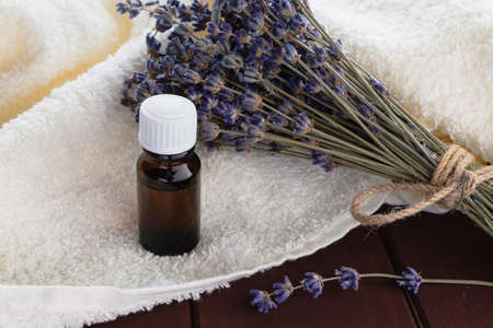 In a dark bottle, essential oil and a bunch of dry lavender on a white terry towel. The concept of body care, spa treatments, aromatherapy.の写真素材