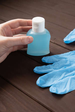 medical latex gloves, a bottle with antiseptic liquid and a mans hand on a brown background against a new coronavirusの写真素材