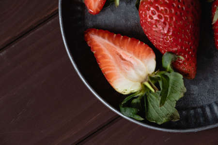 Half and whole berries of organic strawberries lie on a gray metal plate top view. Copy Space. Background of the kitchen table. Texture.の写真素材