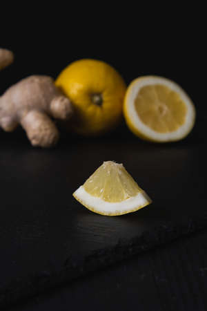 Whole and slices of lemon and ginger on a black background.の写真素材