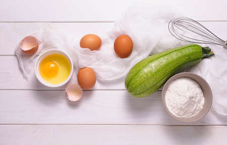 The process of cooking a dish of zucchini eggs and flour on a wooden kitchen tableの写真素材