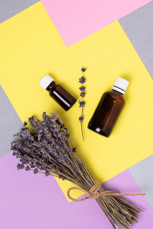 A bunch of dried lavender and oil in a bottle against a background of colorful blocks.の写真素材
