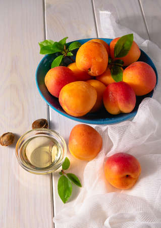 Bright orange ripe apricots in a bowl and apricot oil on a white background.の写真素材