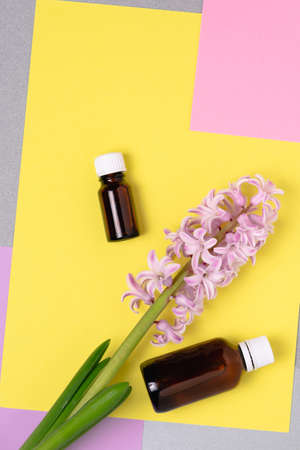 Bottles made of dark glass with a cosmetic product and a hyacinth flower on a background of colored blocks.の写真素材