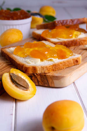 Simple breakfast toast with apricot jam and ripe fresh fruits on a light backgroundの写真素材
