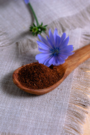 Blue chicory flower and instant powder in a wooden spoon for making a coffee substitute drink. A useful drinkの写真素材
