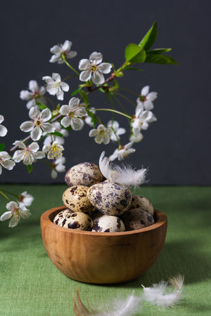 A wooden bowl of quail eggs with a flowering branch stands on the table. Spring Easter card. Texture.の写真素材